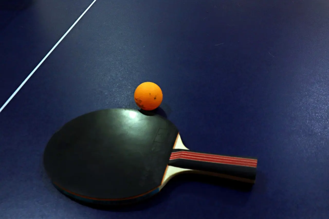 Bordtennisbat og orange bordtennisbold på et bordtennisbord